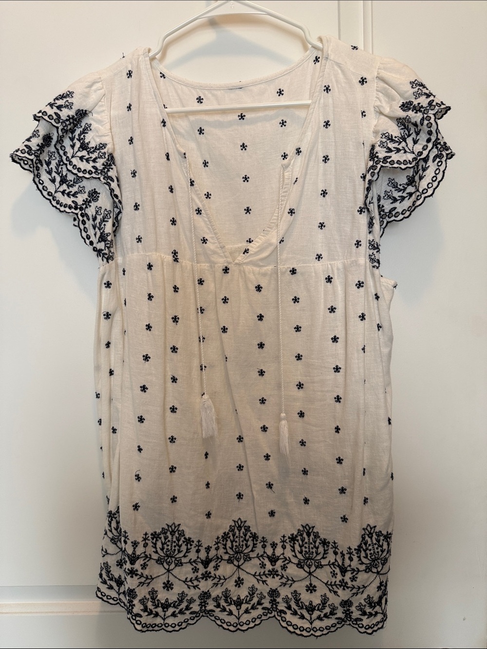 Ruffle-sleeved tunic top with navy blue embroidery.